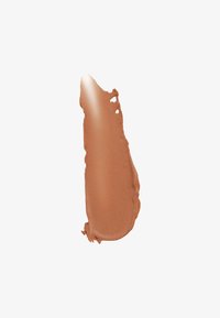 Matte vloeibare formule in een warme, middelbruine tint met een gladde textuur, met een gebogen, onregelmatige rand.