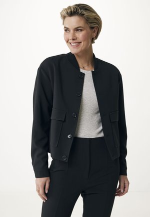 Schwarze Bomberjacke mit einem runden Halsausschnitt, Frontknopfverschluss und zwei Seitentaschen. Über einem hellgrauen Oberteil mit glatter Textur getragen.