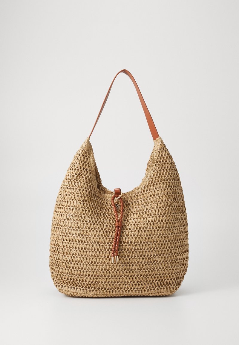 Sac d'épaule tissé couleur fauve avec une bandoulière en cuir tressé et une fermeture à cordon sur un fond blanc uni.