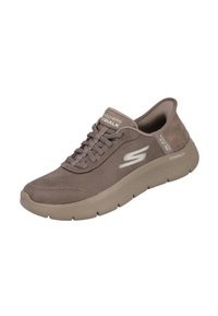 Zapatilla deportiva de ante marrón con diseño de cordones, acolchado ligero, suela gruesa color beige y branding reflectante en el lateral.