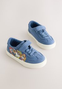 Baskets en toile bleue avec une semelle en caoutchouc blanche, ornées d'un imprimé coloré de personnage de dessin animé sur le côté, avec des fermetures à lacets et à scratch.