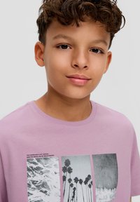 Lila katoenen t-shirt met een frontafbeelding van zwart-witte afbeeldingen van oceaangolven en palmbomen, ronde hals, korte mouwen.