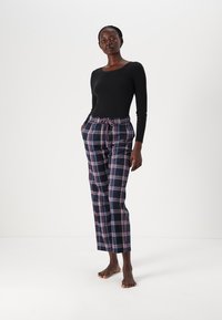 Black long-sleeve top paired with purple and navy plaid pajama pants featuring an elastic waistband and drawstring.