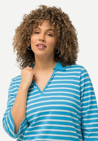 Polo a righe blu e bianche con scollo a V e maniche a tre quarti, realizzato in tessuto morbido, con colletto blu uniforme.