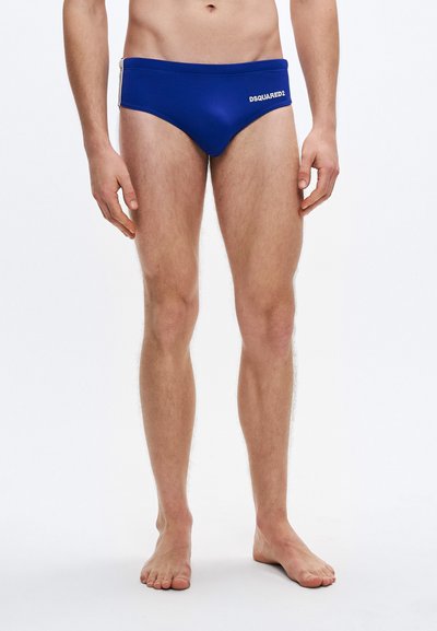 Blue swim briefs made from stretchy fabric, featuring a low-rise cut and a white logo on the front. Smooth texture and minimalistic design.
