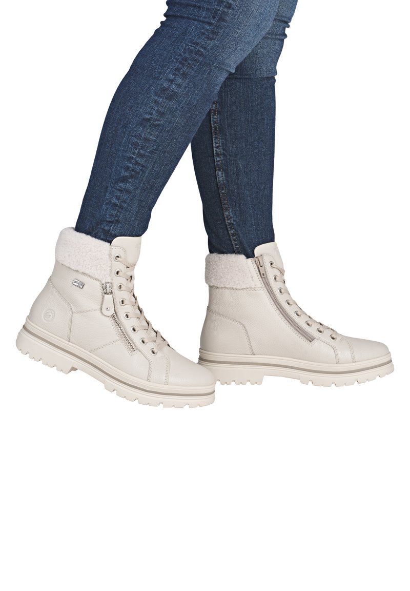 Bottines blanches en cuir avec un col en fausse fourrure, des lacets et une fermeture éclair sur le côté. Semelle extérieure crantée pour une meilleure traction, avec une finition texturée discrète.
