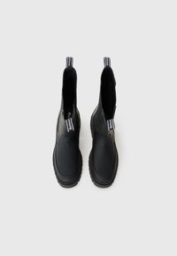 Bottes de cheville en caoutchouc noir au design épuré, présentant des côtés texturés, une semelle épaisse et des tirettes avec des accents de marque.