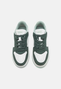 Green and white sneakers with a smooth leather and textured fabric upper, padded collar, and perforated toe box. Features laces and logo.