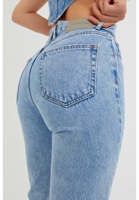 Jeans de tiro alto en azul claro con una textura de denim clásica. Presentan bolsillos traseros, costuras en contraste y un parche con el logo de Pull&Bear.