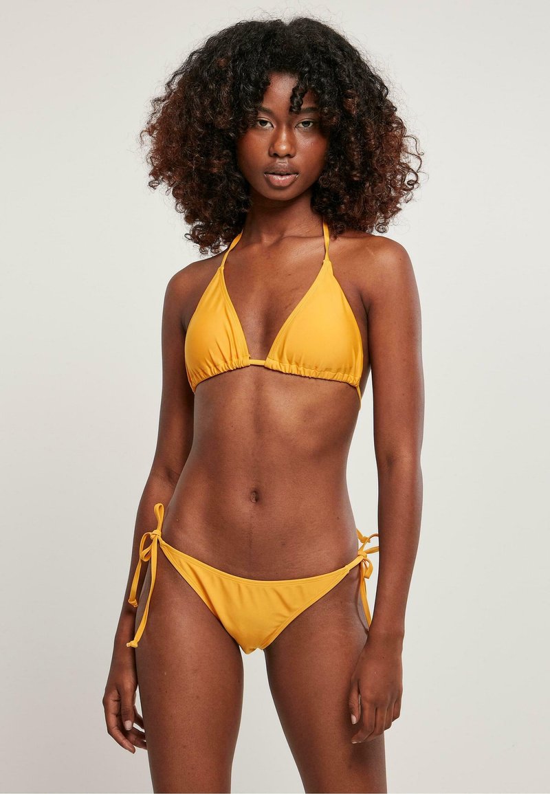 Set di bikini giallo composto da un top a triangolo con centro arricciato e lacci regolabili, abbinato a un bikini bottom a vita bassa con lacci sui lati.