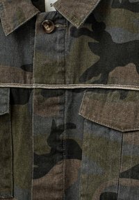 Camo-mønstret skjorte i nuancer af grøn og brun, med knaplukning, to brystlommer og kontrastsying.