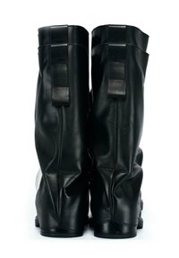 Un paio di stivali in pelle nera a metà polpaccio visti dal retro, dotati di linguette per l'estrazione e una texture leggermente rugosa.