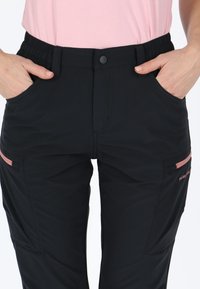 Schwarze Cargo-Hosen mit elastischem Bund, ausgestattet mit Seitentaschen und rosa Akzent-Reißverschlüssen. Hergestellt aus leichtem, strapazierfähigem Material.
