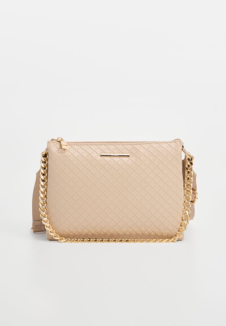 Beige gesteppte Handtasche mit einer goldenen Kettenriemen, ausgestattet mit einem Reißverschluss und einem dezenten Logoakzent auf der Vorderseite. Strukturierte Oberflächendetails.