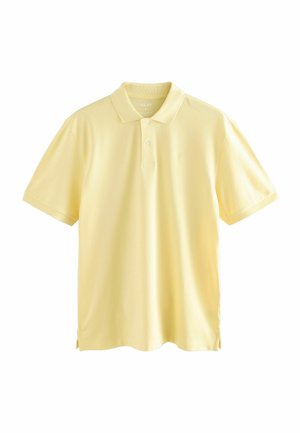 Camisa polo amarilla hecha de algodón suave, con un collar clásico, mangas cortas y un pequeño logo en el pecho. Aberturas laterales en el dobladillo.