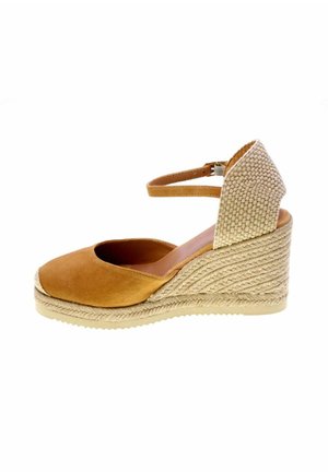 Espadrillas zeppa in camoscio marrone con tacco in fibra naturale intrecciata e cinturino alla caviglia con chiusura a fibbia, mostrata di profilo.
