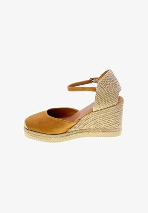 Espadrillas zeppa in camoscio marrone con tacco in fibra naturale intrecciata e cinturino alla caviglia con chiusura a fibbia, mostrata di profilo.