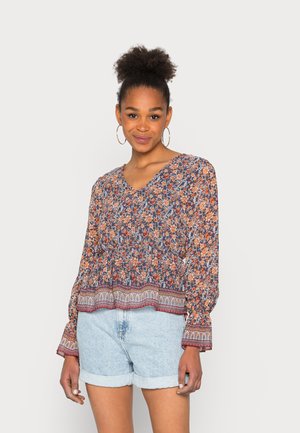 Blusa floral com decote em V, mangas longas e cintura elástica em azul marinho, laranja e creme. Apresenta uma bainha estampada e tecido leve.