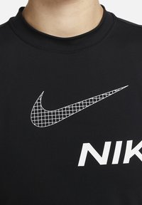 Černá mikina s velkým bílým logem Nike. Logo obsahuje mřížkový vzor na zakřiveném svoshu. Hladká atmletická struktura látky.