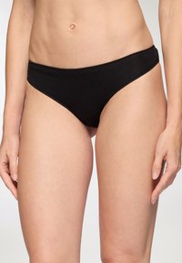 Perizoma in cotone nero con una texture liscia, design a vita bassa e copertura minima sui lati. Presenta bordi puliti e rifiniti.