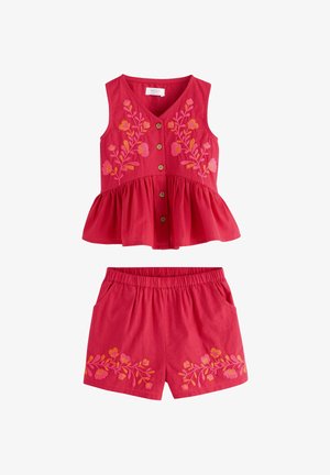Top roșu fără mâneci cu nasturi și peplum și pantaloni scurți asortați, ambele având broderie florală în nuanțe de roz și portocaliu.