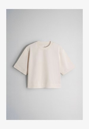 Beżowy krótki t-shirt z krótkim rękawem i okrągłym dekoltem na jasnoszarym tle.