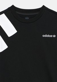 Μαύρο t-shirt με κοντά μανίκια, με τρεις λευκές ρίγες στον αριστερό ώμο και μικρό λευκό λογότυπο Adidas στο στήθος.