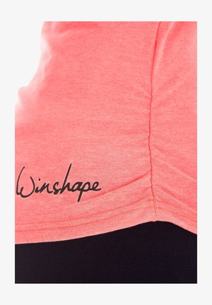 Korálovo ružový športový top s pozbieraným bočným švom a čiernym logom "Winshape" potlačeným v dolnom ľavom rohu. Mäkka, textúrovaná tkanina.