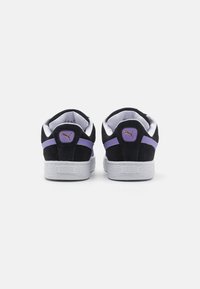 Baskets en daim noir avec des accents violets, une doublure intérieure blanche et des semelles en caoutchouc gris texturé. Logo sur le talon et le côté. Design classique.