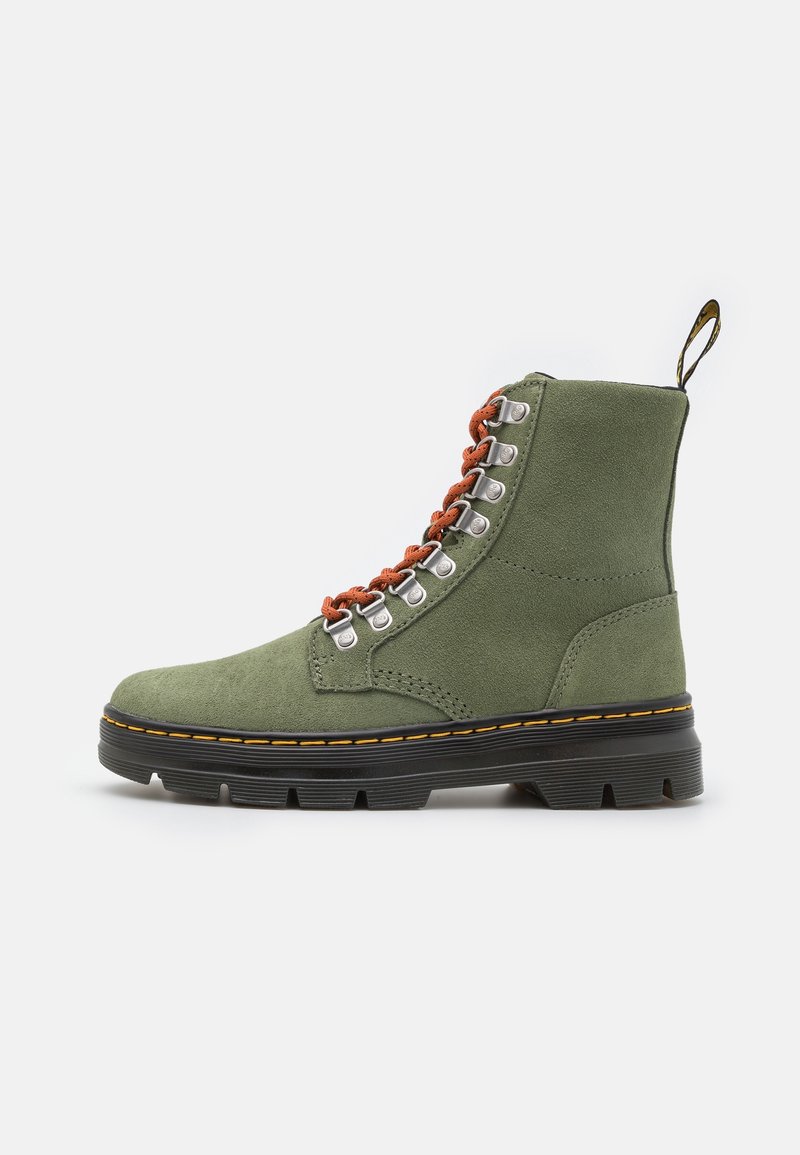 Botte montante en daim vert avec semelle noire épaisse, lacets orange, œillets argentés et détails de couture jaunes sur fond blanc.