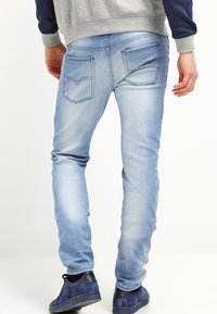 Ljusblå denimjeans med slim fit, som har två vinklade bakfickor och subtila sömnadsdetaljer. Bärs med mörkblå sneakers.