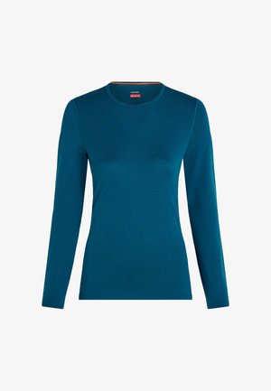 Long-sleeve, crew neck merino wool base layer shirt in deep teal blue, displayed on a white background.
