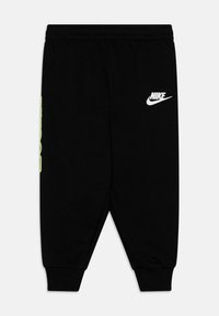 Pantaloni sportivi neri in cotone, con vita elasticizzata, polsini a costine e logo Nike bianco con accenti verdi sui lati.