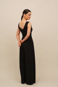 Melnā kombinezonā ir pieguļošs augšdaļa un platām kājām. Tam ir zems aizmugure un tanka tipa siksnas, tas izgatavots no gludas auduma ar minimālām šuvēm.