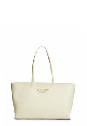 Sac fourre-tout beige avec deux longues poignées et logo "tommy jeans" embossé sur le devant, texture de cuir simple et lisse.