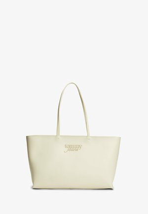 Beżowa torba typu tote z dwoma długimi uchwytami i wytłoczonym logo "tommy jeans" z przodu, prosta i gładka faktura skóry.