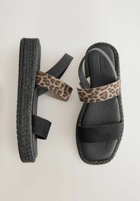 Svarta plattformssandaler med vävd svart jute-detalj. Funkar med leopardmönstrade och enfärgade svarta tygremmar. Platt, öppen tå-design.