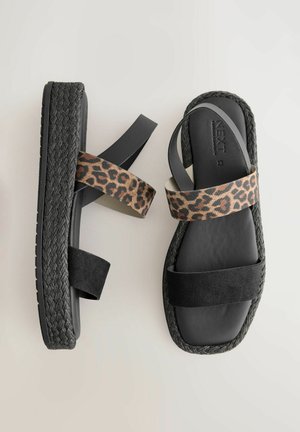 Mustad platvormsandalid musta põimitud jute detailiga. Omab leopardimustriga ja täismustade kangastrappe. Lame, avatud varba disain.