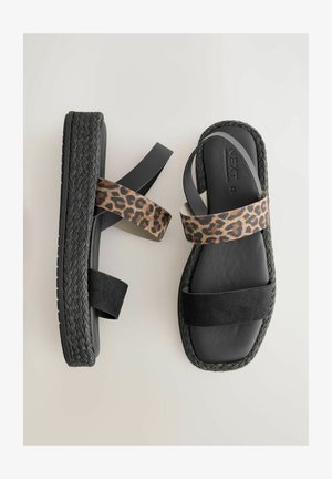 Sandalias de plataforma negras con detalle de yute negro trenzado. Cuentan con tiras de tela de leopardo y negra sólida. Diseño plano y abierto en la puntera.