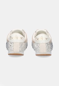Zapatillas blancas y beige con adornos de brillantes en el talón, suela de goma y logo "BeFree" en la parte trasera.