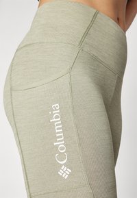 Vaaleanvihreät ribattut legginsit, joissa on korkea vyötärö ja sivutasku. Jalkaan on painettu iso valkoinen Columbia-logo.