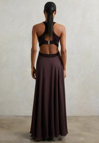 Voogav tume burgundi kleit, millel on fikseeritud bodice ja avatud selg, ainulaadse rihma kujundusega ja peidetud lukuga vööl.