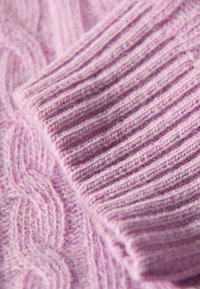 Ljuslila stickad tröjtyg med både fläta och ribbat mönster, mjuk ullblandning med en fluffig yta och synliga sömminnen.