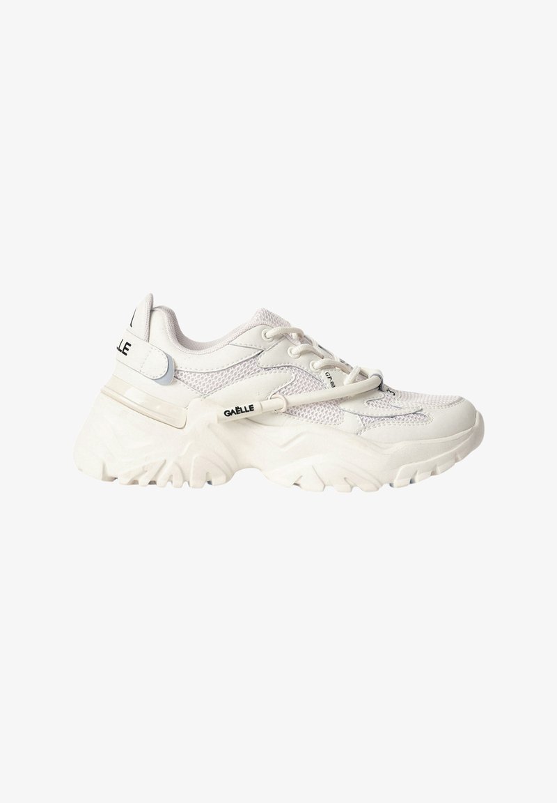 Scarpe sportive bianche realizzate in rete e materiali sintetici, dotate di una suola spessa, design con lacci e dettagli del logo sul lato e sul tallone.