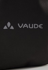 Borsa in tessuto nero con una superficie testurizzata, caratterizzata da un evidente logo grigio "VAUDE" e un emblema grafico triangolare.