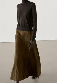 Brown turtleneck sweater paired with a long, flowing brown suede skirt. Smooth texture with a simple, minimal design and elegant drape.