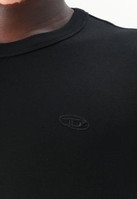 Svart bomulls T-skjorte med rund hals og brodert logo. Stoffet har en jevn og glatt tekstur. Enkel design, uten mønstre eller aksenter.