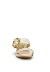 Witte sandaal met hakken, voorzien van gestructureerde banden, een gouden gesp accent en een gladde beige voetbed. Open teen ontwerp met een lage hak.