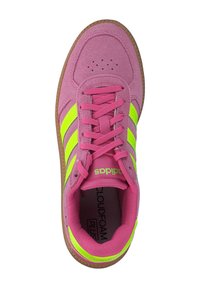 Ružové semišové tenisky s neónovo zelenými pruhmi, okrúhlou špičkou a hnedou gumovou podrážkou. Súčasťou sú ploché šnúrky a perforované detaily na špičke.