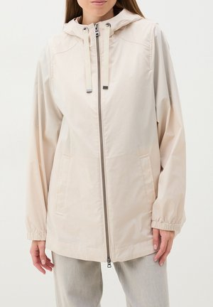 Chaqueta ligera beige con capucha, cremallera frontal y dos bolsillos laterales. Presenta puños elásticos y una textura suave y mate.